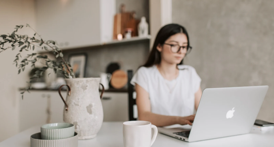 Woman working remotely on a laptop in white & gray kitchen