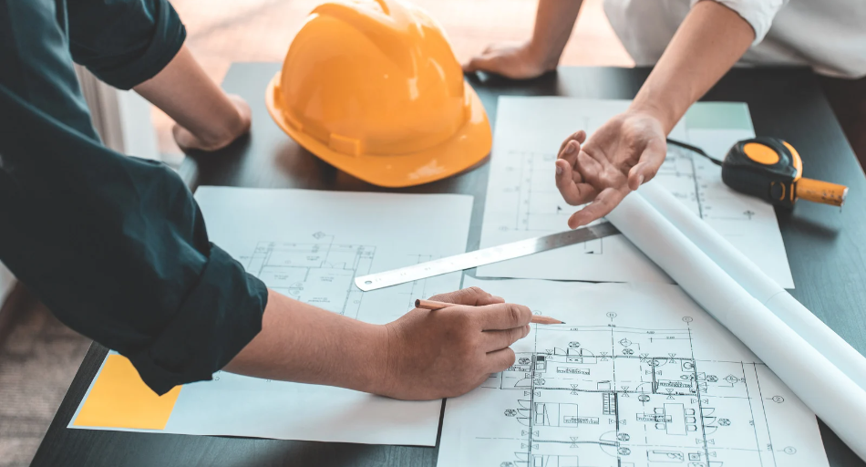 engineering professionals collaborating with hard hat on table