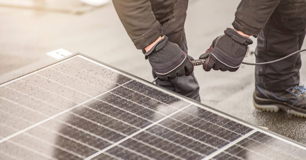 solar panel installer connects modules together using electrical cable