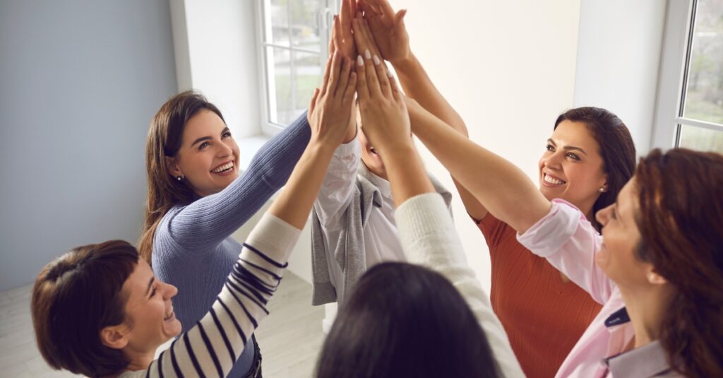 team of happy employees joining hands in collaboration