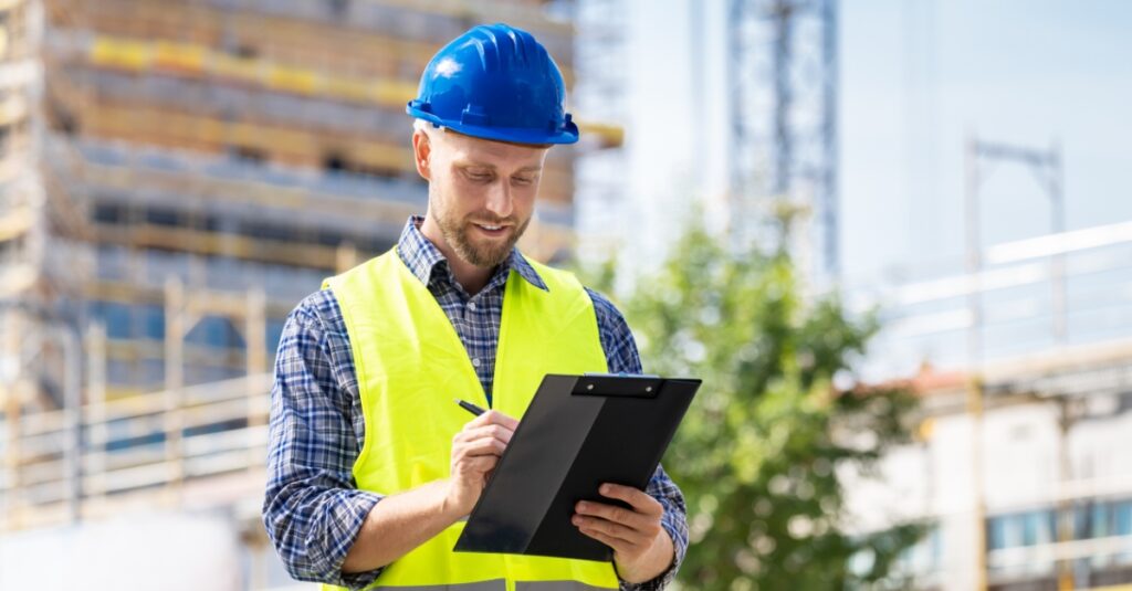 OSHA inspector at construction site wearing hi vis vest and blue hard hat